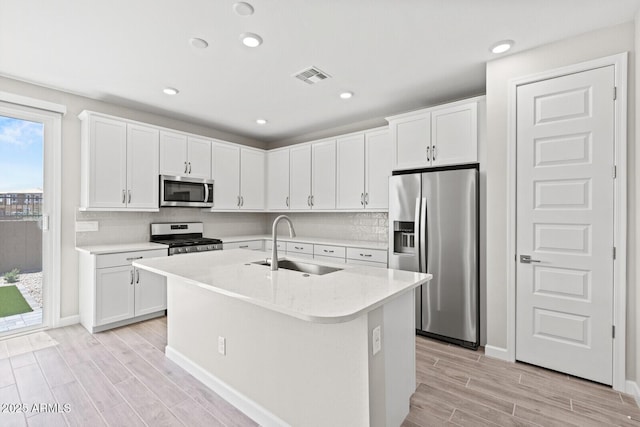 21047 N 58th Way, Phoenix, AZ 85054 - kitchen featuring appliances with stainless steel finishes, a sink, wood tiled floors, white cabinetry, and a center island with sink