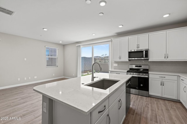 21047 N 58th Way, Phoenix, AZ 85054 - kitchen with appliances with stainless steel finishes, a sink, light wood-type flooring, tasteful backsplash, and recessed lighting