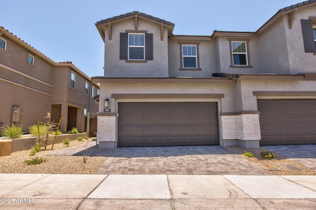 21047 N 58th Way, Phoenix, AZ 85054 - view of front of house with a garage, stucco siding, decorative driveway, and stone siding