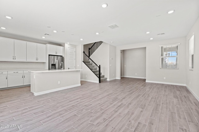 21047 N 58th Way, Phoenix, AZ 85054 - unfurnished living room with recessed lighting, light wood-type flooring, baseboards, and stairs