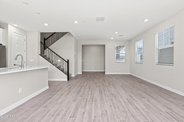 21047 N 58th Way, Phoenix, AZ 85054 - unfurnished living room featuring light wood finished floors, baseboards, a sink, and recessed lighting