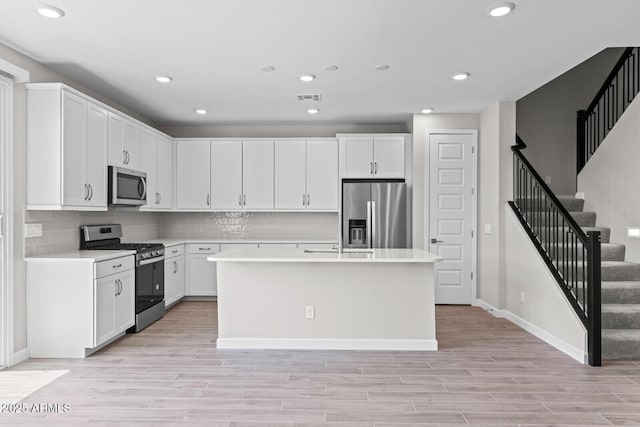 21047 N 58th Way, Phoenix, AZ 85054 - kitchen with stainless steel appliances, light countertops, white cabinets, light wood-style flooring, and recessed lighting