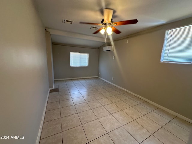 empty room featuring ceiling fan, light tile patterned floors, and a wall mounted air conditioner