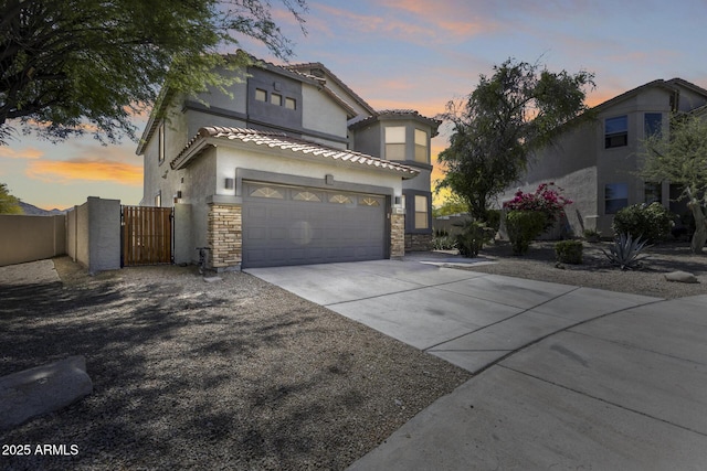 18103 W Canyon Ln, Goodyear, AZ 85338 - view of front of home with a gate, driveway, stone siding, and a garage