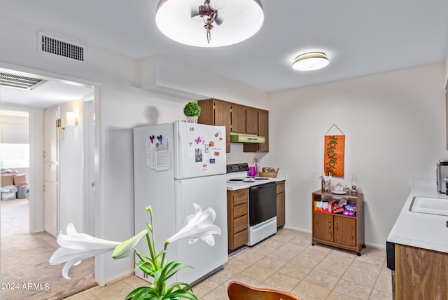 kitchen featuring light countertops, white appliances, visible vents, and under cabinet range hood