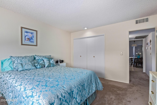 carpeted bedroom with a textured ceiling, visible vents, and a closet