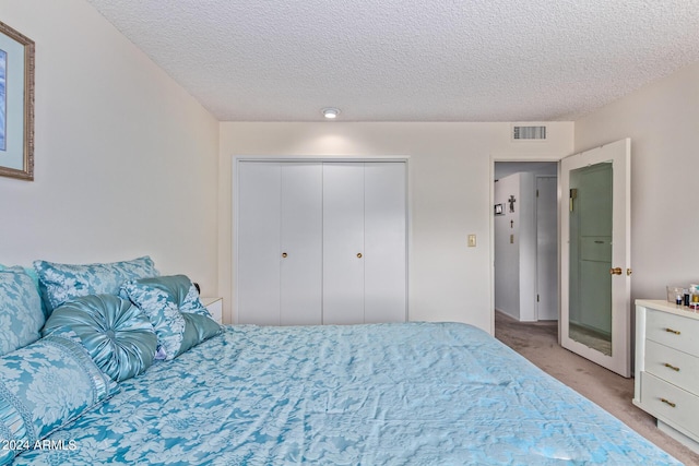 bedroom featuring light carpet, a textured ceiling, visible vents, and a closet