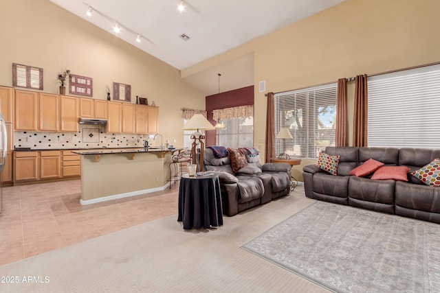 living room featuring high vaulted ceiling, light tile patterned floors, and sink