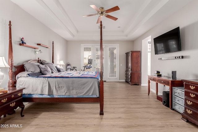 bedroom featuring a raised ceiling, ceiling fan, and light hardwood / wood-style flooring