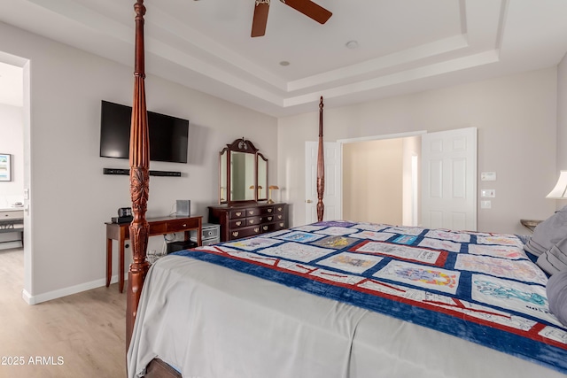 bedroom featuring a raised ceiling, ceiling fan, and light hardwood / wood-style flooring