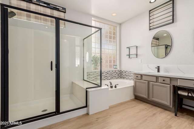 bathroom featuring shower with separate bathtub, wood-type flooring, and vanity