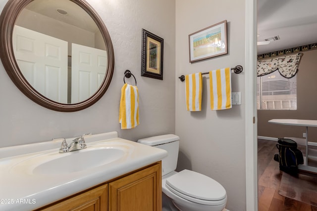 bathroom featuring toilet, vanity, and wood-type flooring