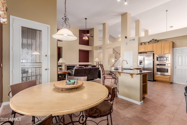 dining area featuring ceiling fan, sink, and a high ceiling