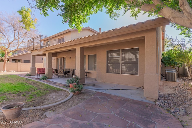 rear view of property featuring central AC unit, a balcony, and a patio