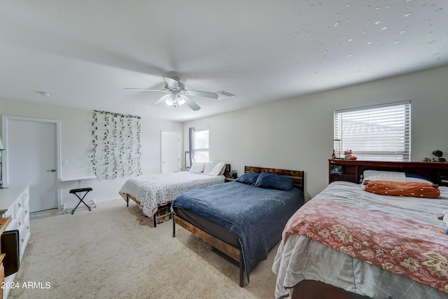 bedroom featuring ceiling fan, multiple windows, and light colored carpet