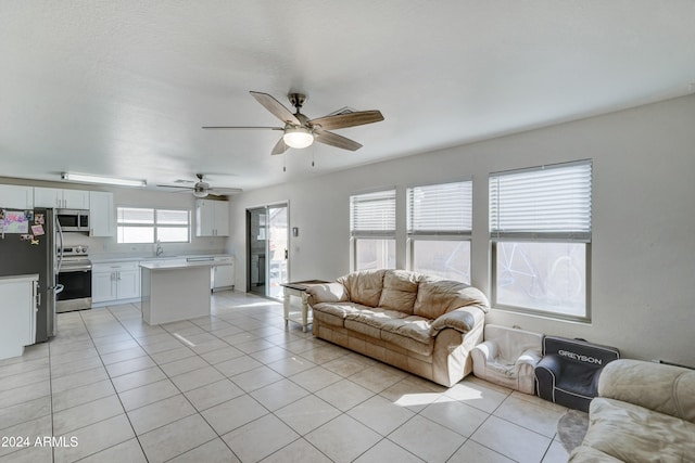 living room featuring sink, ceiling fan, and light tile patterned flooring