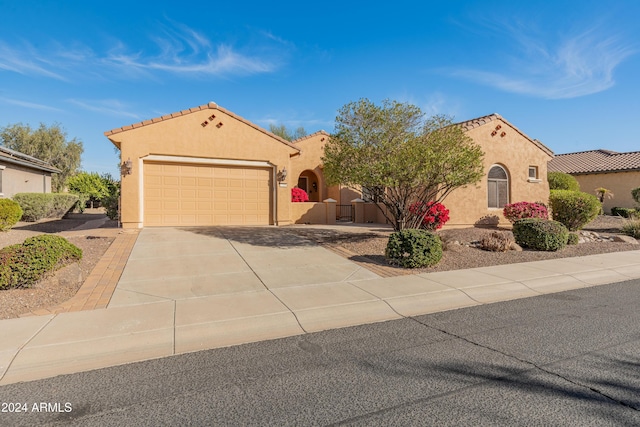 mediterranean / spanish-style house with a garage, driveway, a tiled roof, and stucco siding