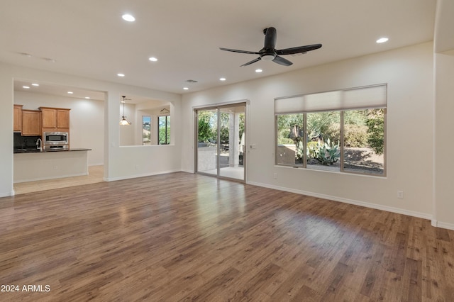 unfurnished living room featuring ceiling fan and hardwood / wood-style flooring