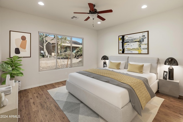 bedroom with baseboards, wood finished floors, visible vents, and recessed lighting