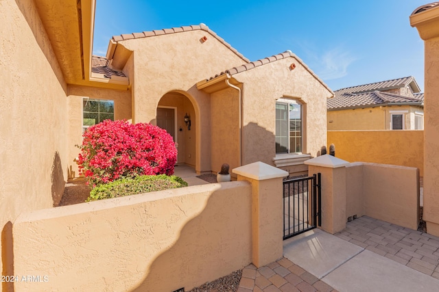 exterior space with fence, a tile roof, a gate, and stucco siding