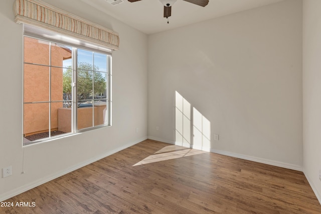 unfurnished room featuring a ceiling fan, visible vents, baseboards, and wood finished floors