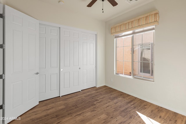 unfurnished bedroom with ceiling fan, wood finished floors, visible vents, baseboards, and a closet