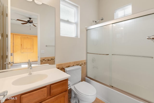 full bathroom with vanity, ceiling fan, tile walls, enclosed tub / shower combo, and toilet