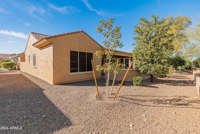 view of side of property featuring a patio area, a tile roof, and stucco siding