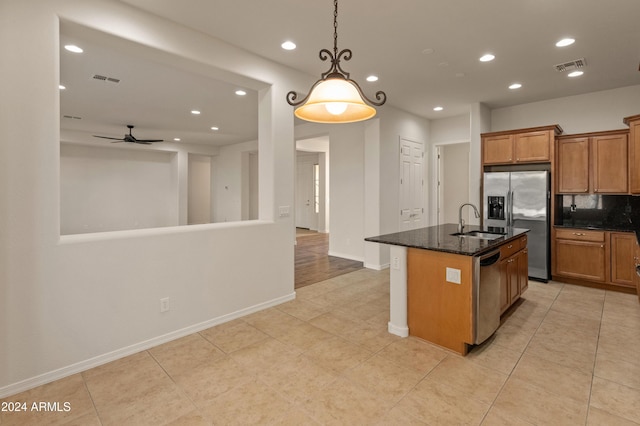 kitchen with appliances with stainless steel finishes, dark stone counters, ceiling fan, sink, and pendant lighting