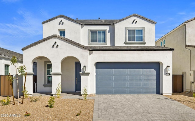 view of front facade featuring decorative driveway, an attached garage, fence, and stucco siding