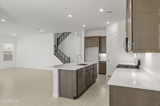 kitchen featuring visible vents, appliances with stainless steel finishes, a sink, light countertops, and an island with sink