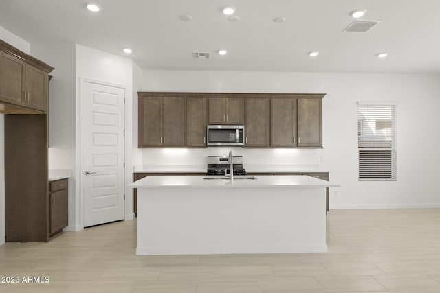 kitchen featuring visible vents, light countertops, appliances with stainless steel finishes, and a kitchen island with sink