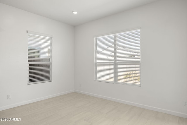 spare room with baseboards, plenty of natural light, and recessed lighting