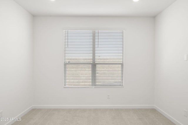 empty room featuring baseboards and light carpet
