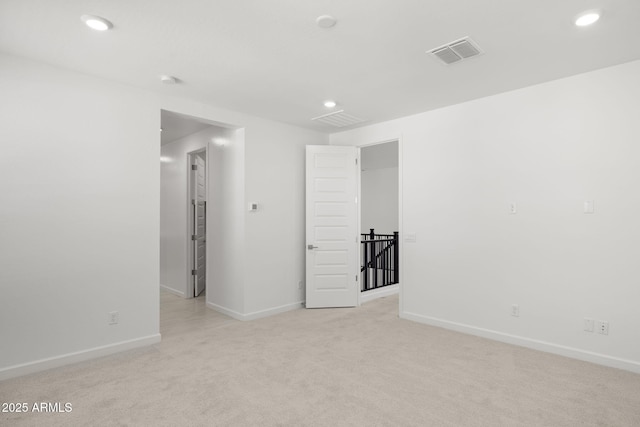 empty room with baseboards, light colored carpet, recessed lighting, and visible vents