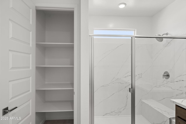 bathroom with a marble finish shower and vanity