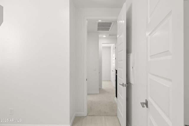 hall featuring visible vents, baseboards, and light carpet