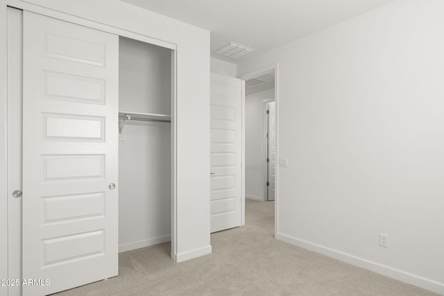 unfurnished bedroom featuring baseboards, light carpet, a closet, and visible vents