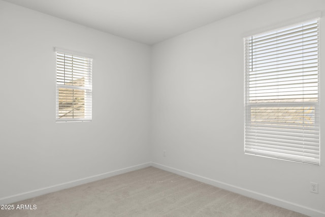 empty room featuring baseboards, plenty of natural light, and light colored carpet