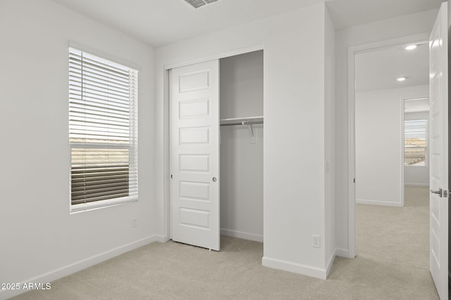 unfurnished bedroom with recessed lighting, baseboards, light carpet, and a closet