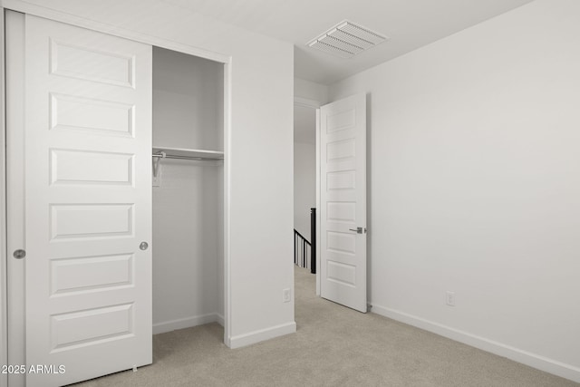 unfurnished bedroom with baseboards, visible vents, light carpet, and a closet