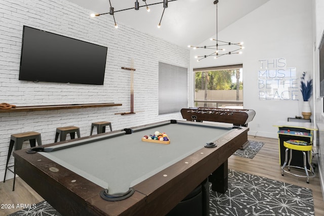 rec room featuring high vaulted ceiling, hardwood / wood-style floors, and brick wall