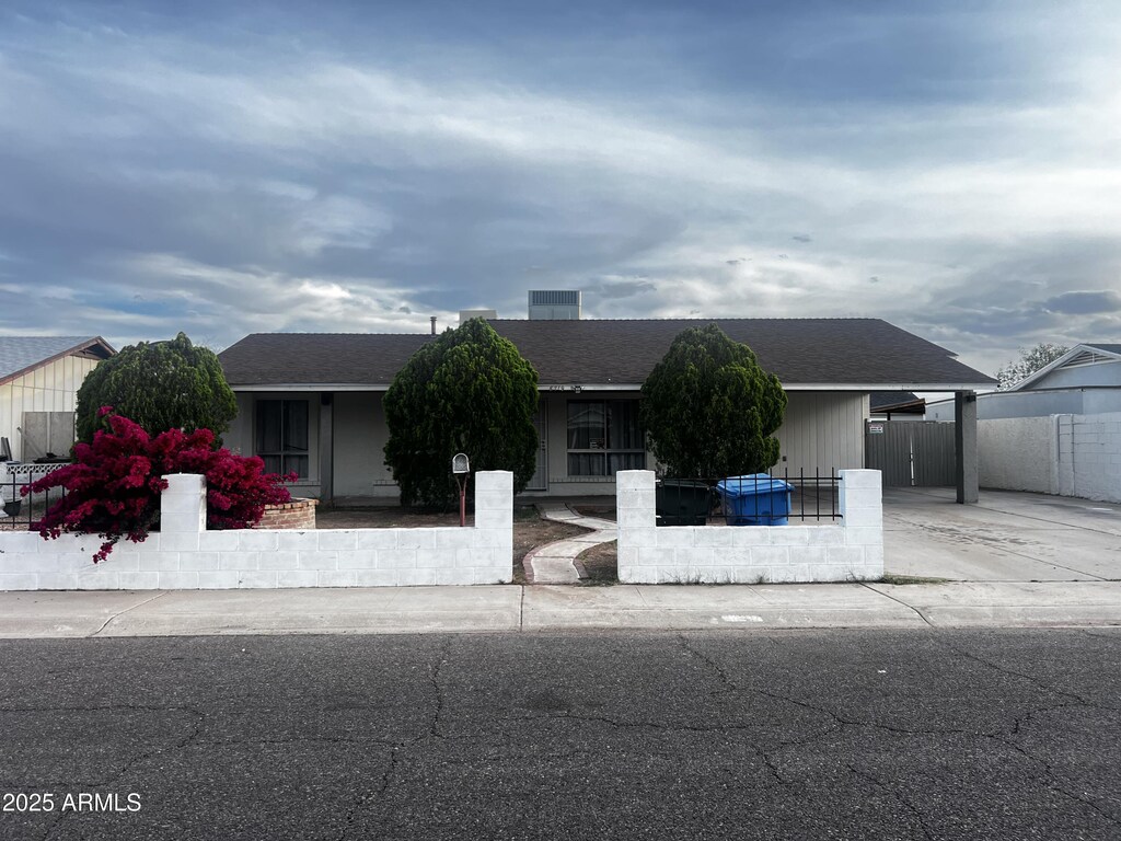 view of front of property with roof with shingles, driveway, and fence