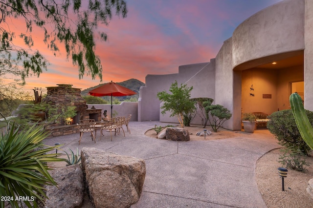 patio terrace at dusk with an outdoor stone fireplace