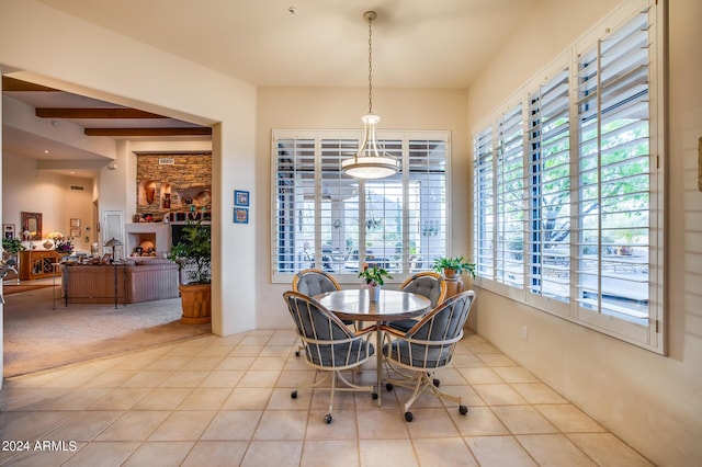 tiled dining room featuring beamed ceiling and a healthy amount of sunlight