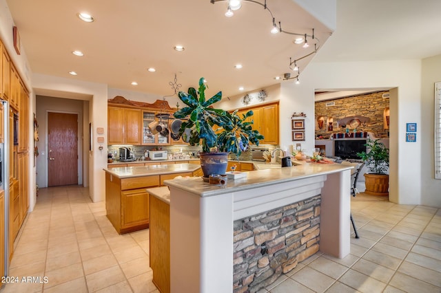 kitchen featuring kitchen peninsula, light tile patterned floors, a kitchen island, and sink