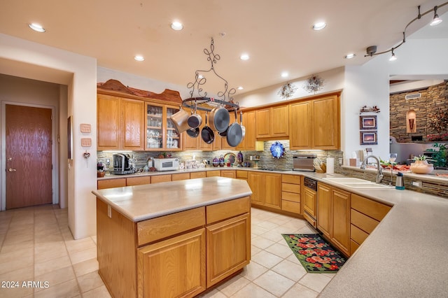 kitchen with decorative backsplash, sink, light tile patterned floors, a kitchen island, and hanging light fixtures