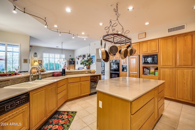 kitchen featuring sink, wine cooler, decorative light fixtures, a kitchen island, and black appliances