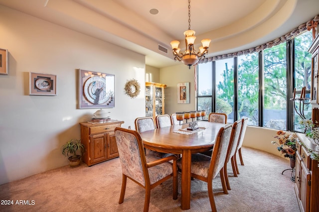 carpeted dining area featuring a tray ceiling and an inviting chandelier