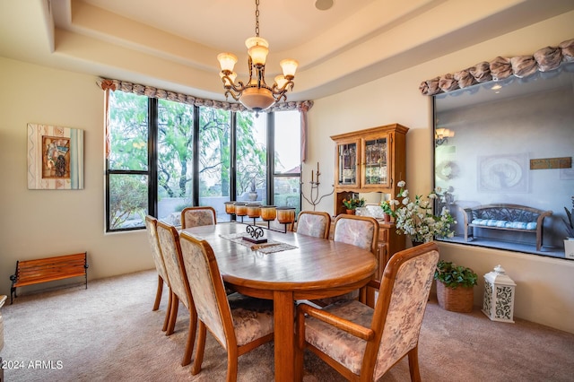 carpeted dining room with a notable chandelier and a raised ceiling